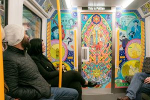 Customers sitting on a Tyne and Wear Metro train in front of artwork