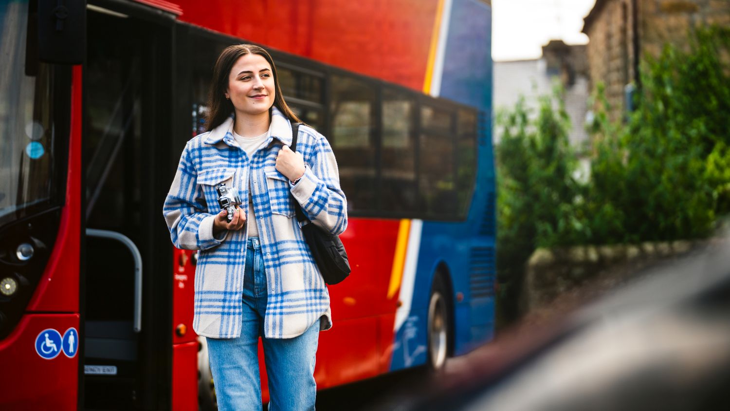 A bus customer walks in front of a bus